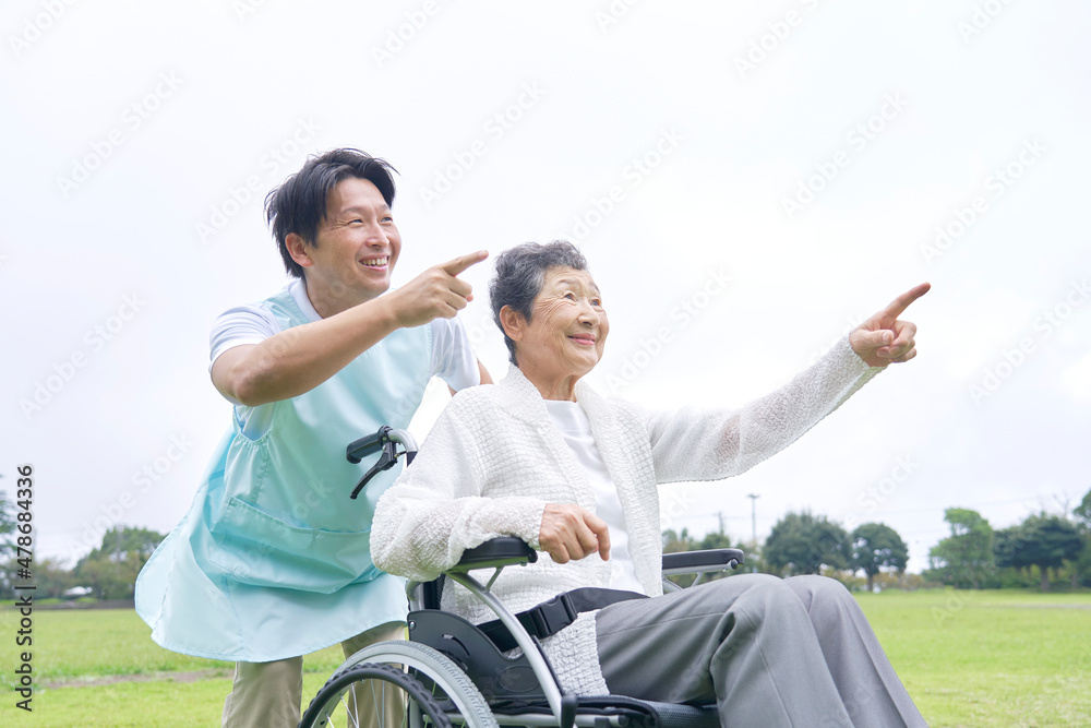 介護士と車椅子に乗る高齢者　屋外