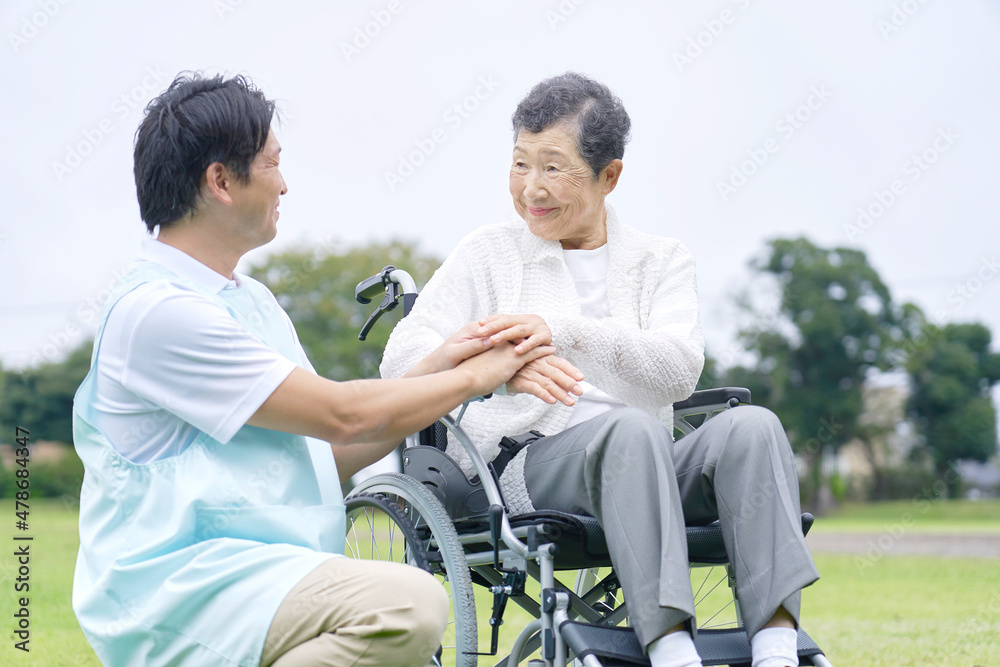 介護士と車椅子に乗る高齢者　屋外