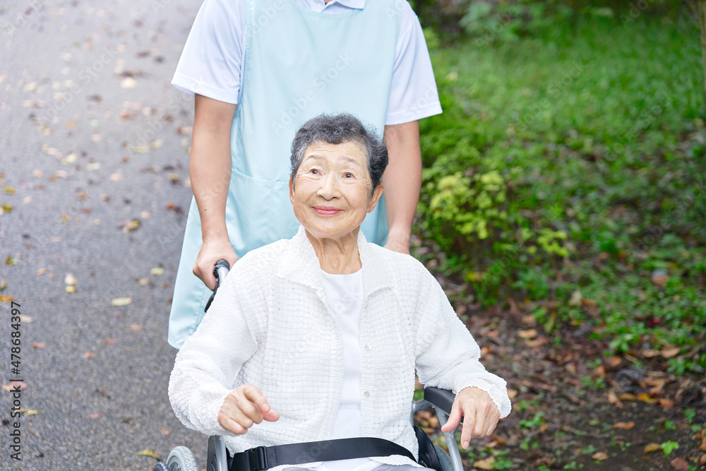 介護士と車椅子に乗る高齢者　屋外