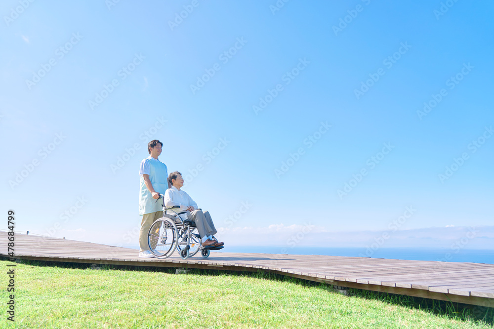 介護士と車椅子に乗る高齢者　屋外