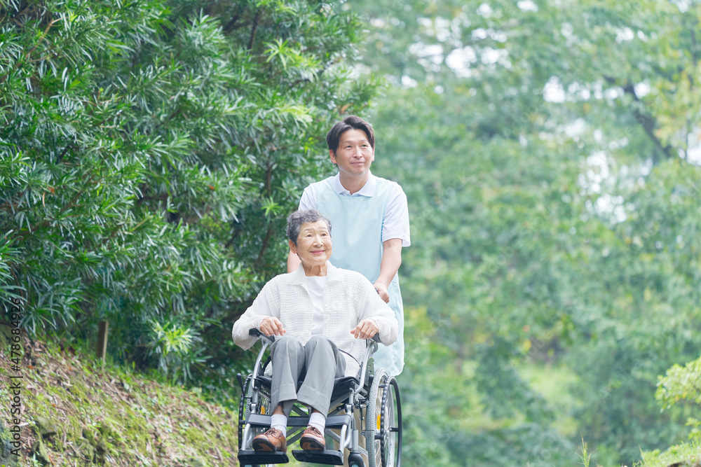 介護士と車椅子に乗る高齢者　屋外