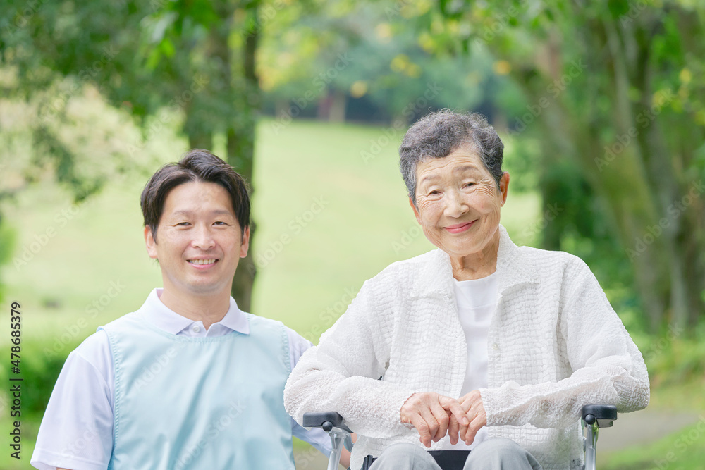 介護士と車椅子に乗る高齢者　屋外