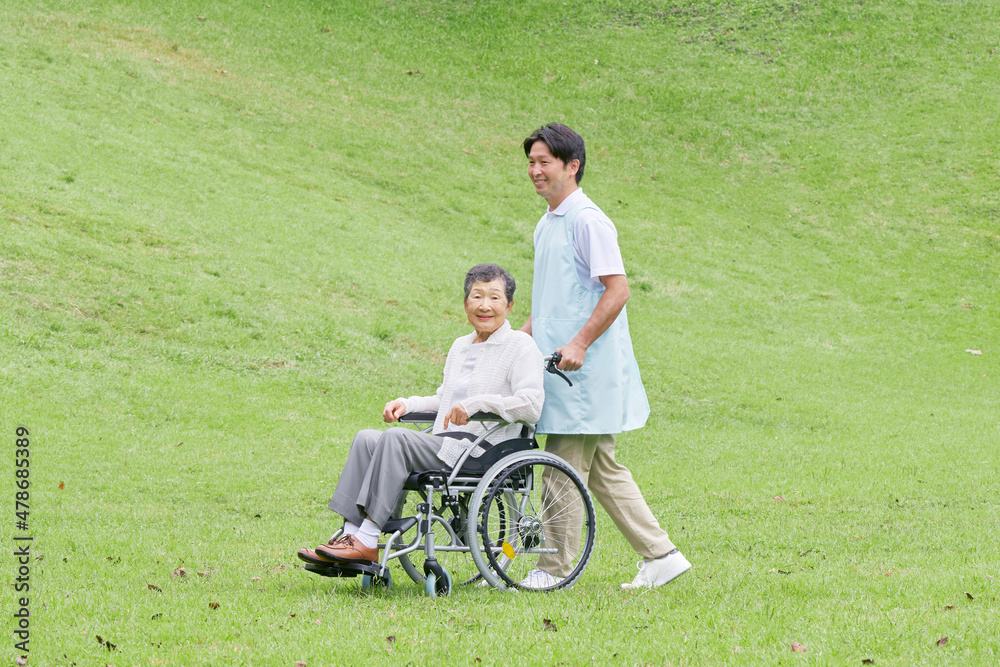 介護士と車椅子に乗る高齢者　屋外