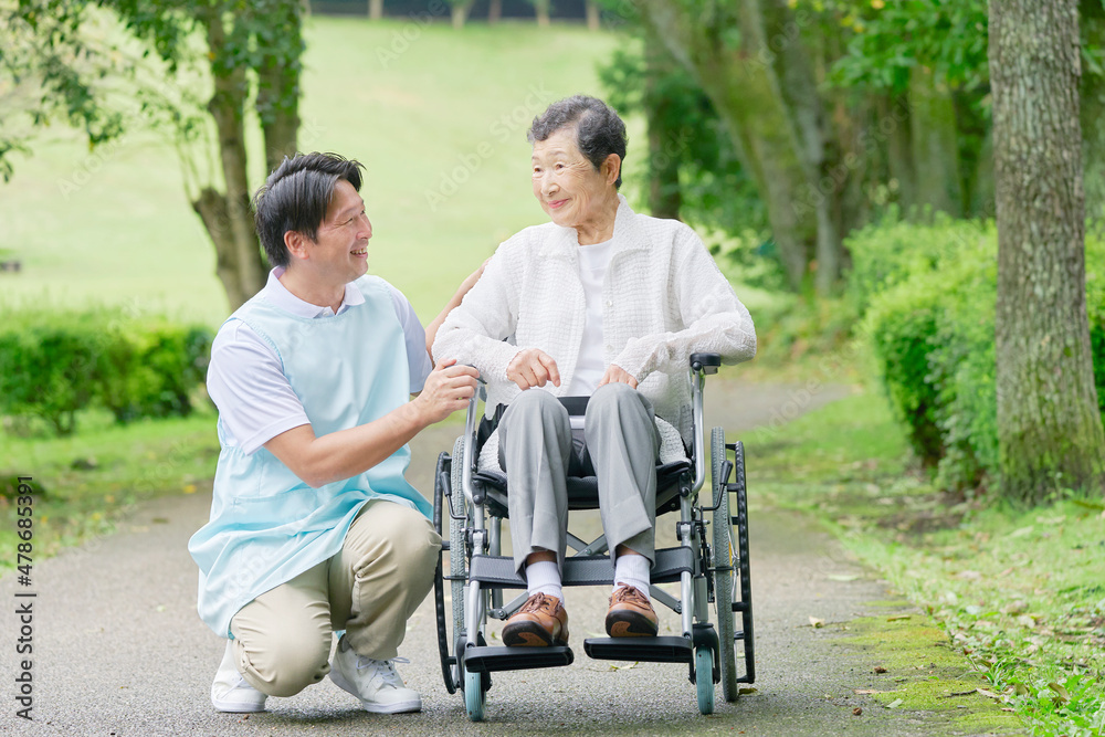 介護士と車椅子に乗る高齢者　屋外