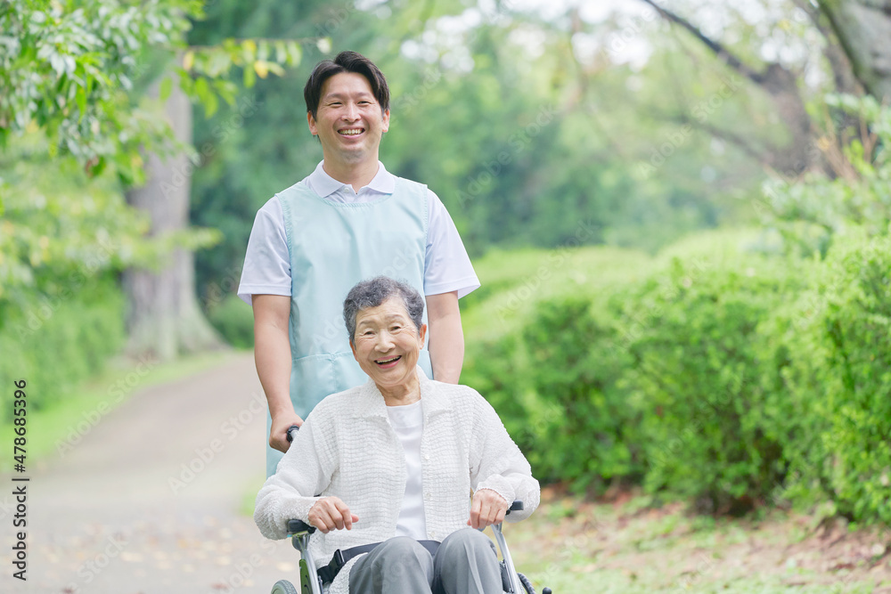 介護士と車椅子に乗る高齢者　屋外