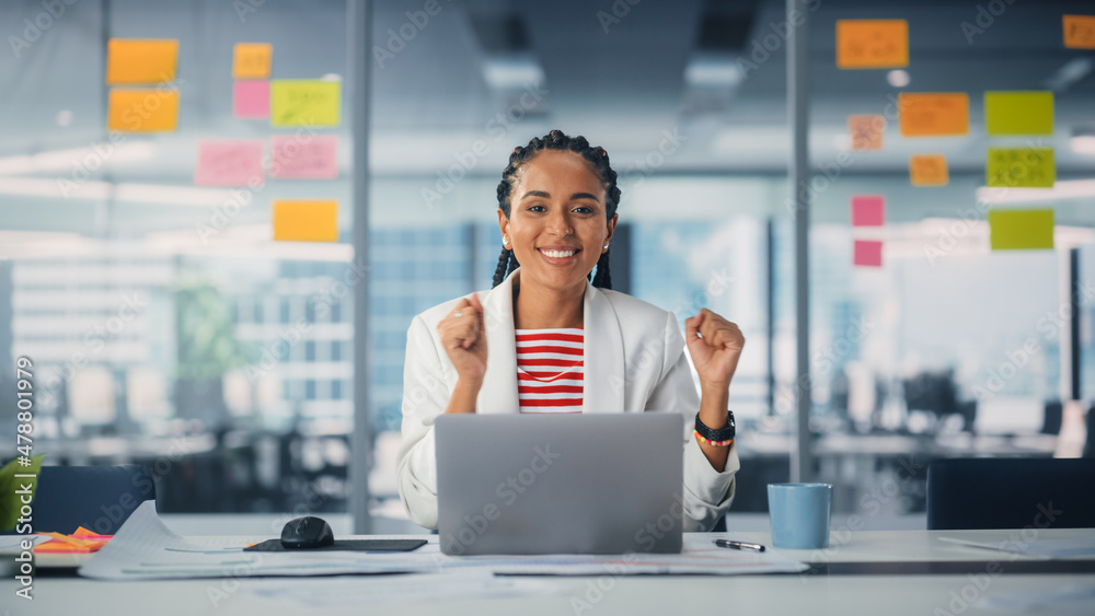 Young Successful Black Project Manager Dances and Smiles While Sitting at Her Desk. Beautiful Female