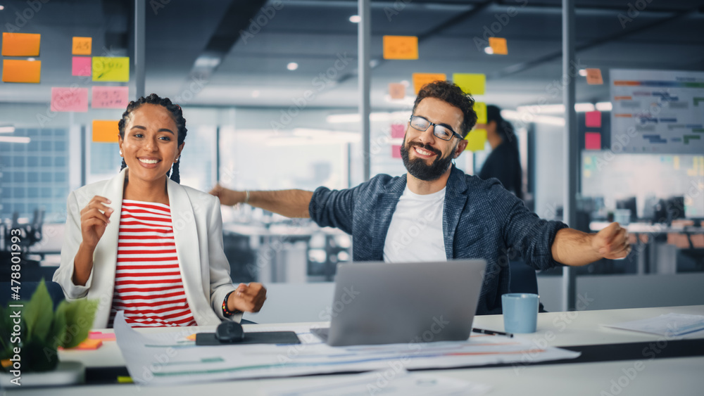 Two Happy Young Professionals in Office: Black Businesswoman and Hispanic Businessman Dance Together