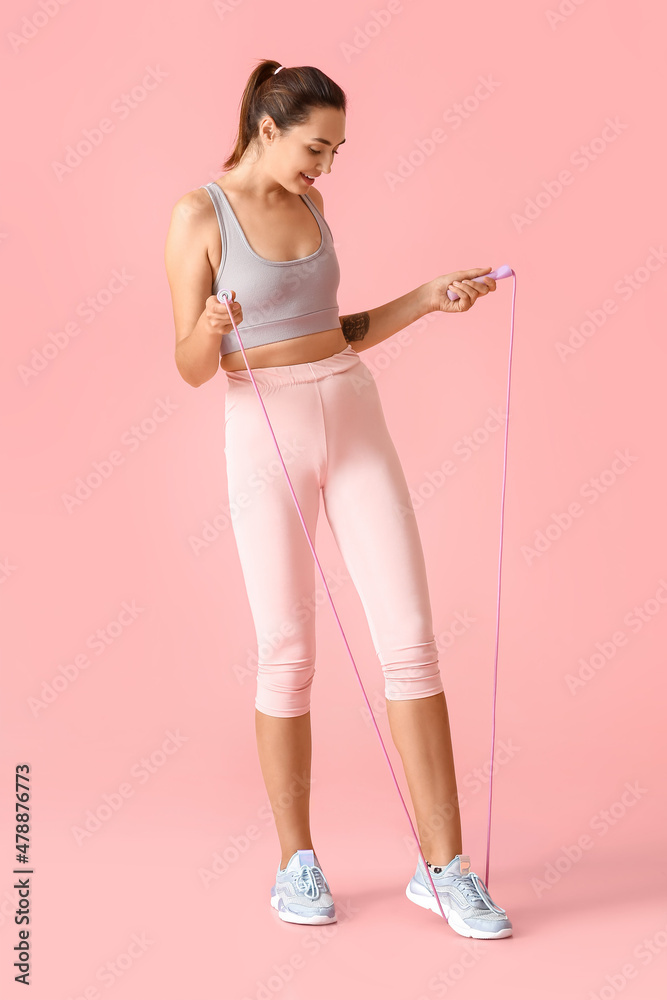 Sporty young woman with skipping rope on color background