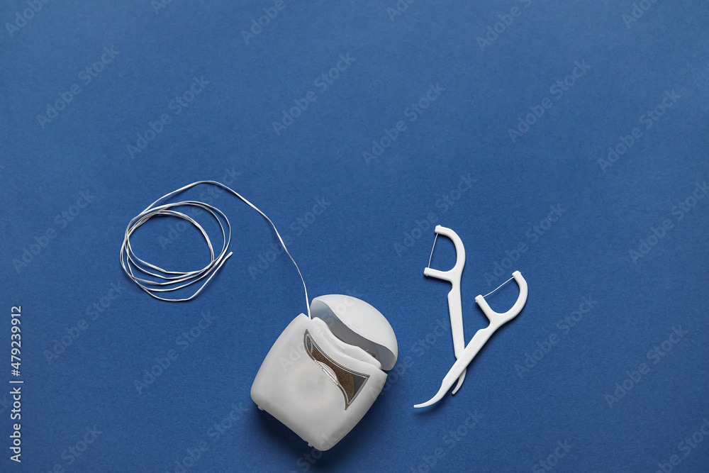 Dental floss and toothpicks on blue background