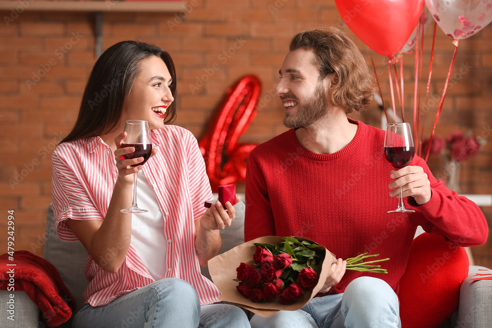 Happy engaged couple drinking wine at home on Valentines Day