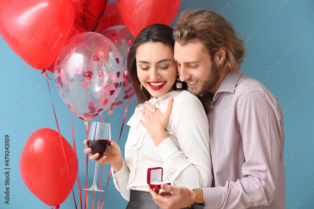 Young man proposing to his girlfriend on color background. Valentines Day celebration