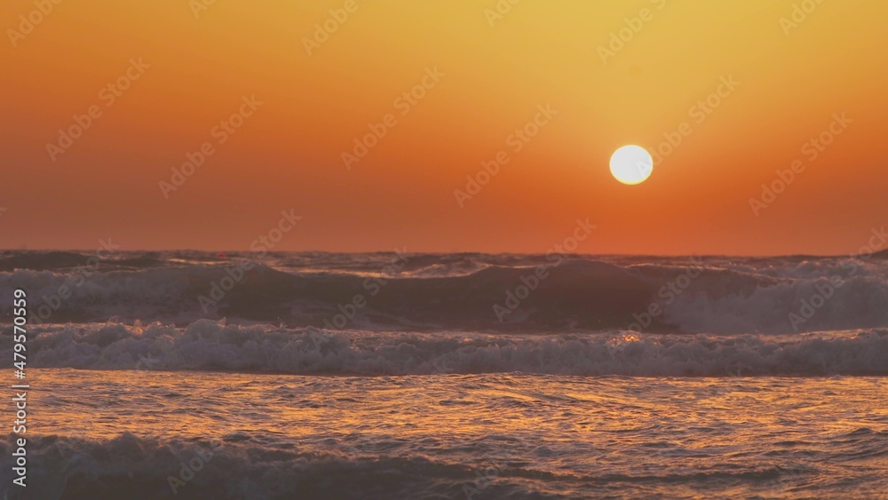 太阳在平静的日落中照耀在海面上。波涛汹涌的海面上的自然暖色。海浪W