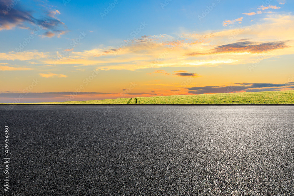 Asphalt road and green field nature landscape at sunset