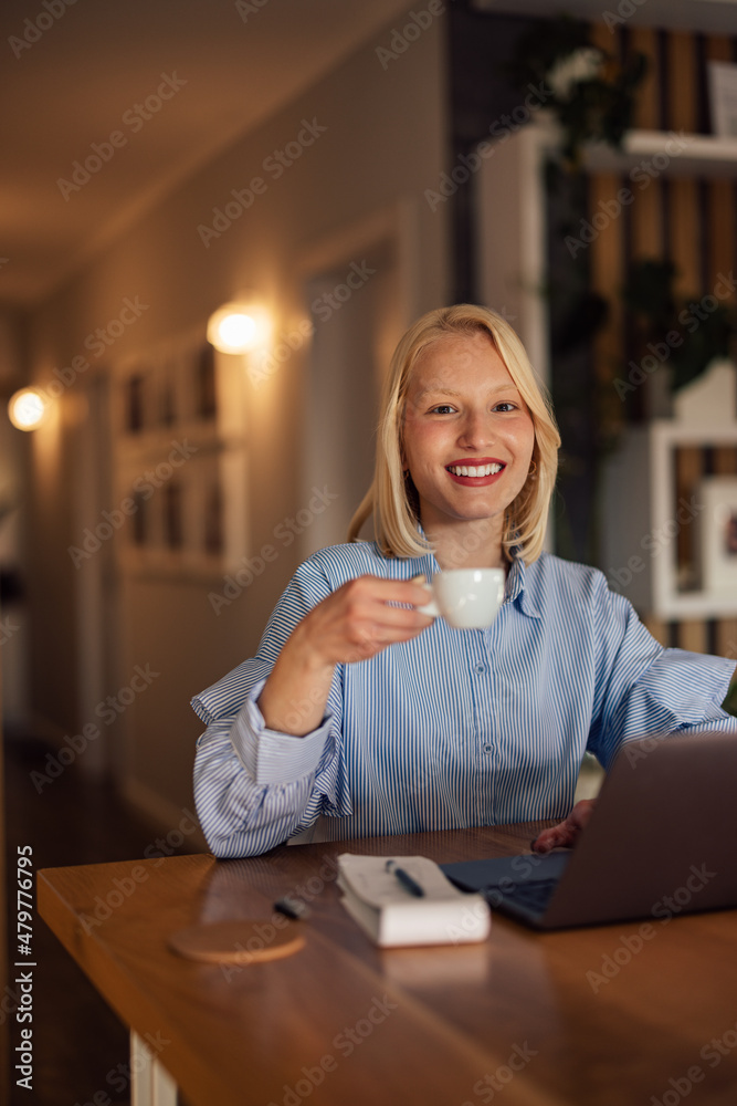 快乐的高加索女人的画像，她在上班前喝着早上的咖啡。