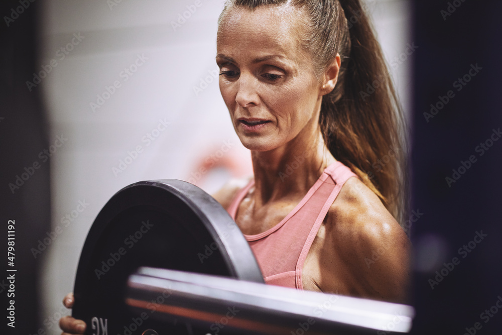 Fit mature woman preparing for a gym weightlifting session