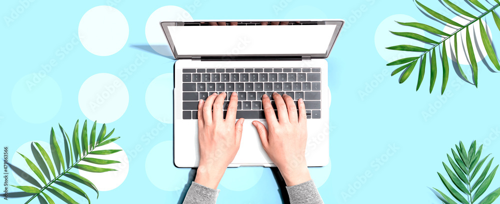 Person using a laptop computer with tropical leaves from above