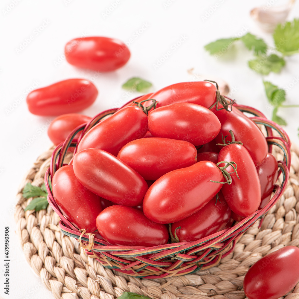 Fresh cherry tomatoes in a basket with spices.