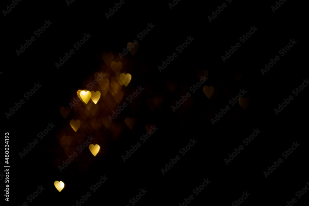 Golden hearts, blurred bokeh lights on black background. Glitter sparkle for celebrate. Overlay for 