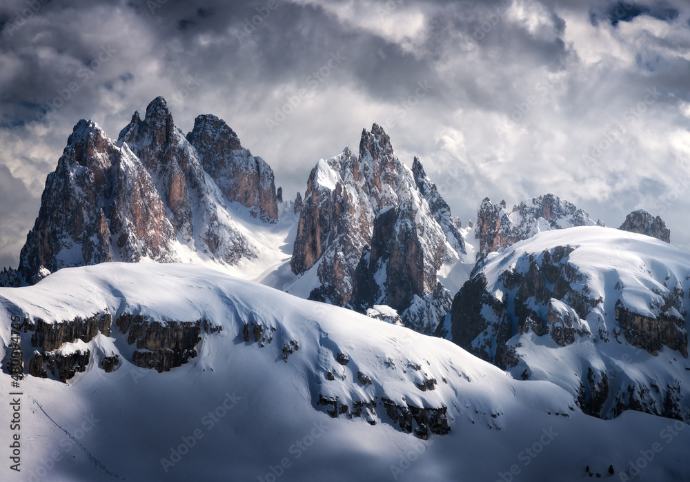 Beautiful mountain peaks in snow in winter. Dramatic landscape with high snowy rocks, overcast sky w