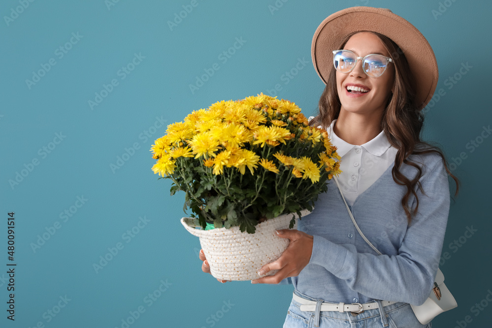 年轻时尚的女人，蓝色背景下拿着美丽的菊花