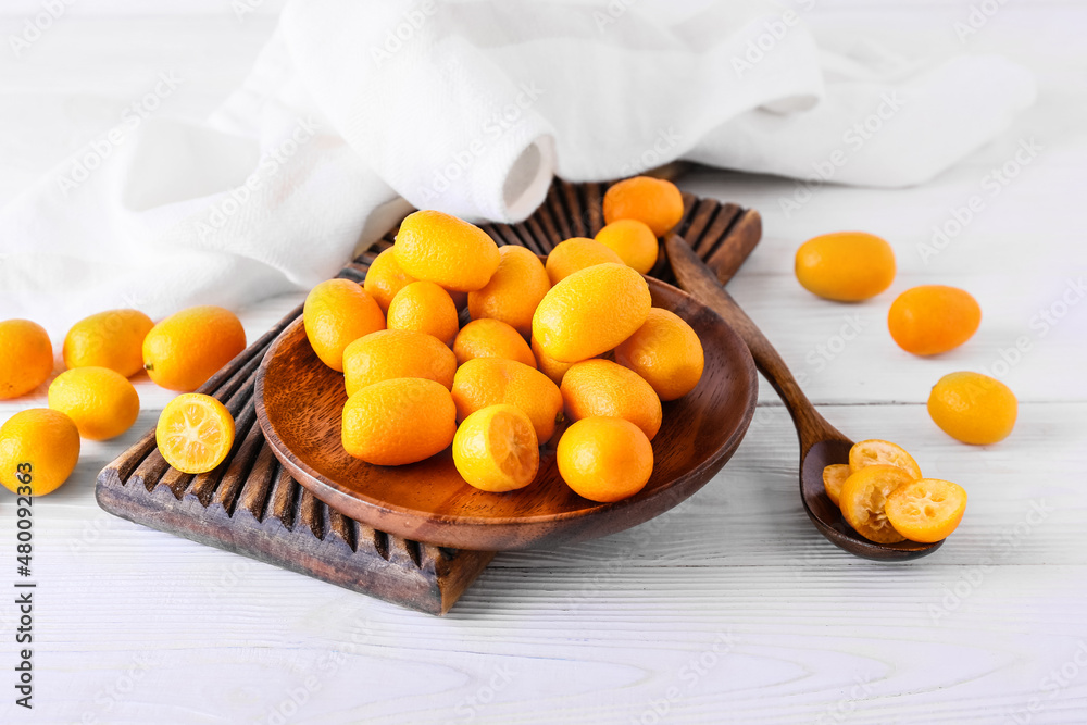 Plate with tasty kumquat fruits on light background