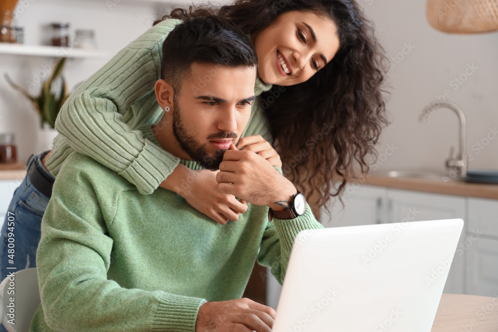 Young couple using laptop in kitchen