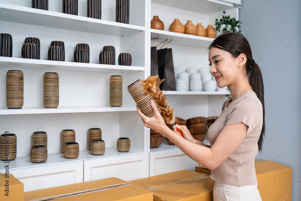 亚洲美女从货架上为客户订购干净的花瓶商品。