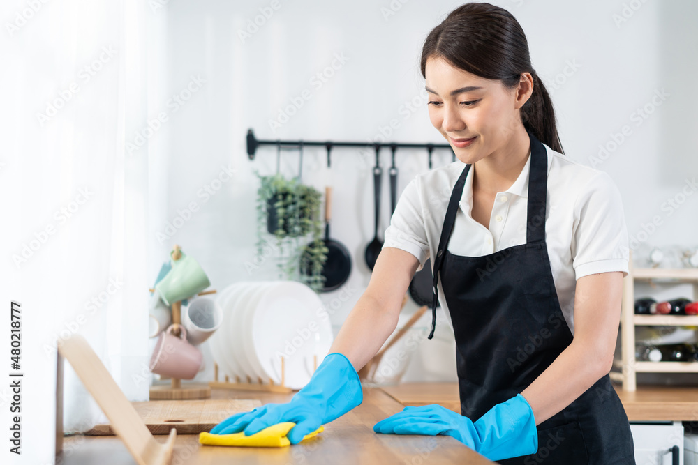 亚洲年轻清洁服务女工在家清洁餐桌。