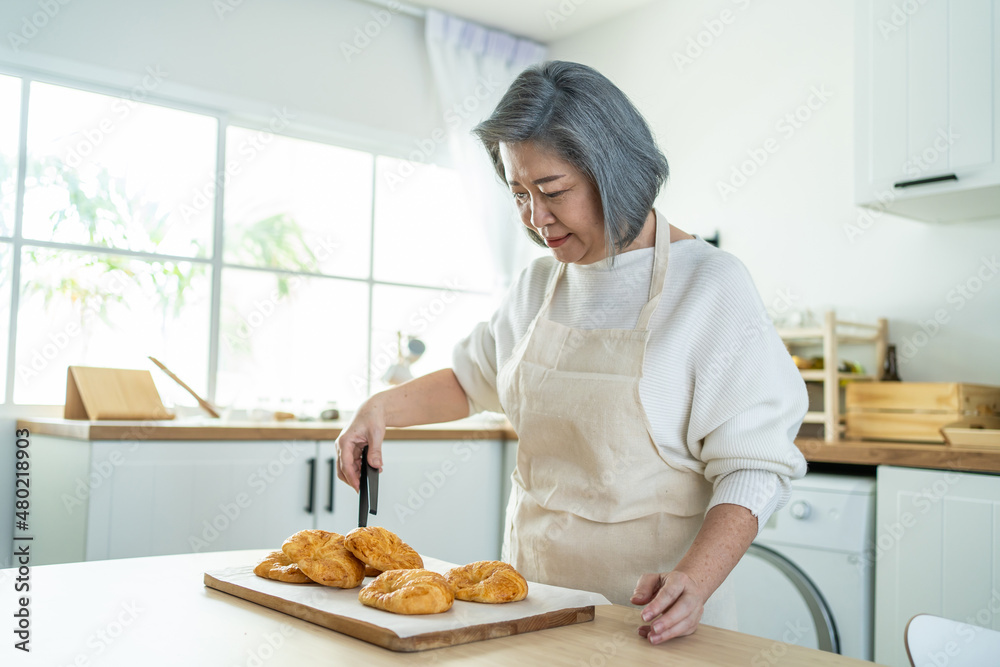 幸福的亚洲老年妇女站在家里的厨房里的肖像。