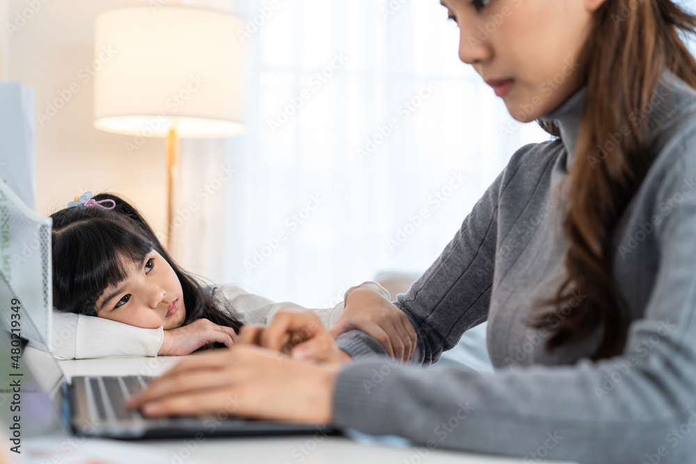 亚洲年幼的女儿感到悲伤，需要和忙碌的母亲一起玩。