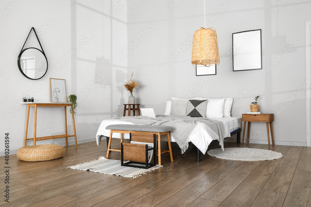 Stylish bench near comfy bed in light bedroom