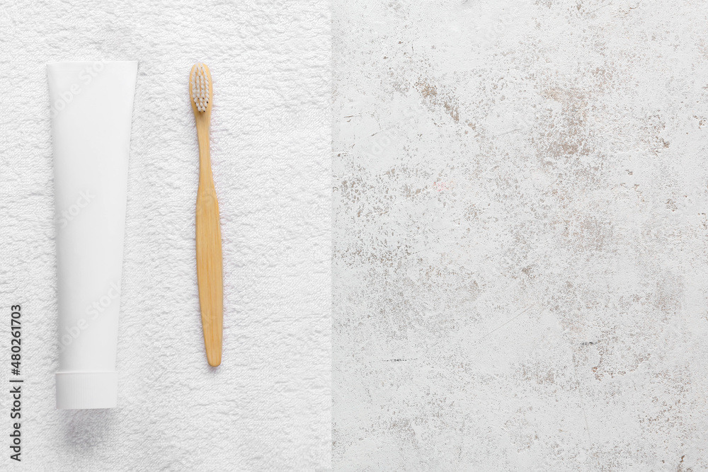 Tube with tooth paste, brush and towel on light background