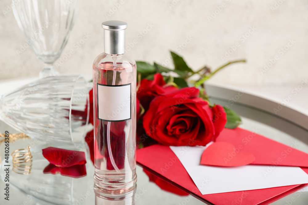 Perfume, envelope and roses for Valentines day on table, closeup