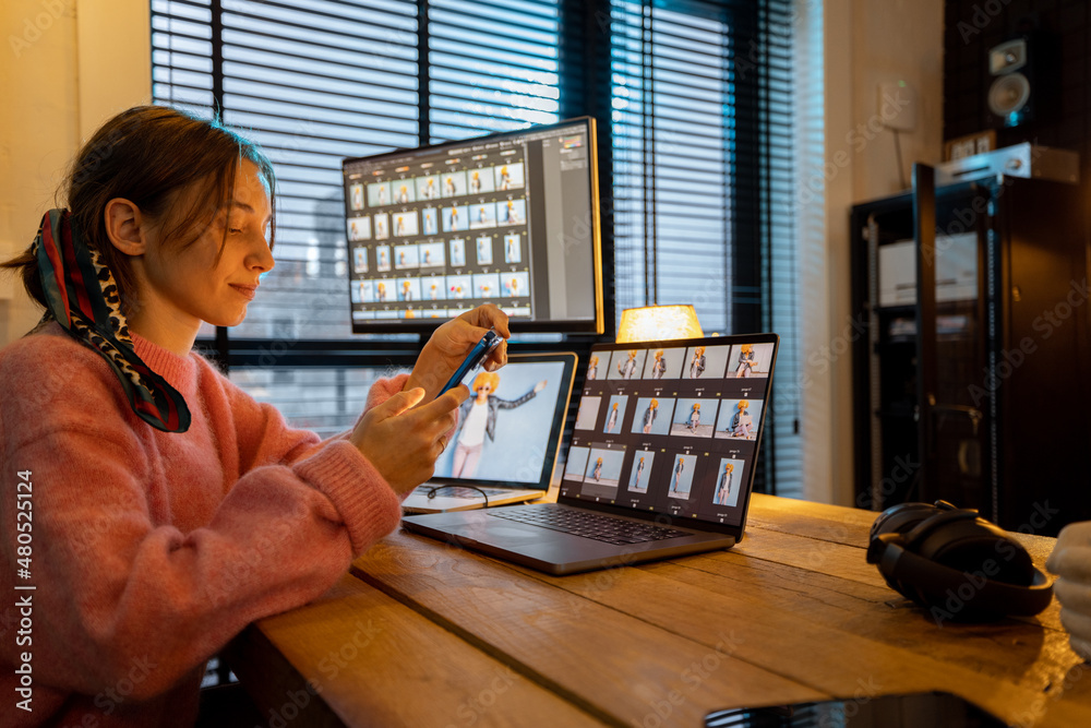 Young creative woman work on phone and computers editing photos at cozy home office. Portrait of fem