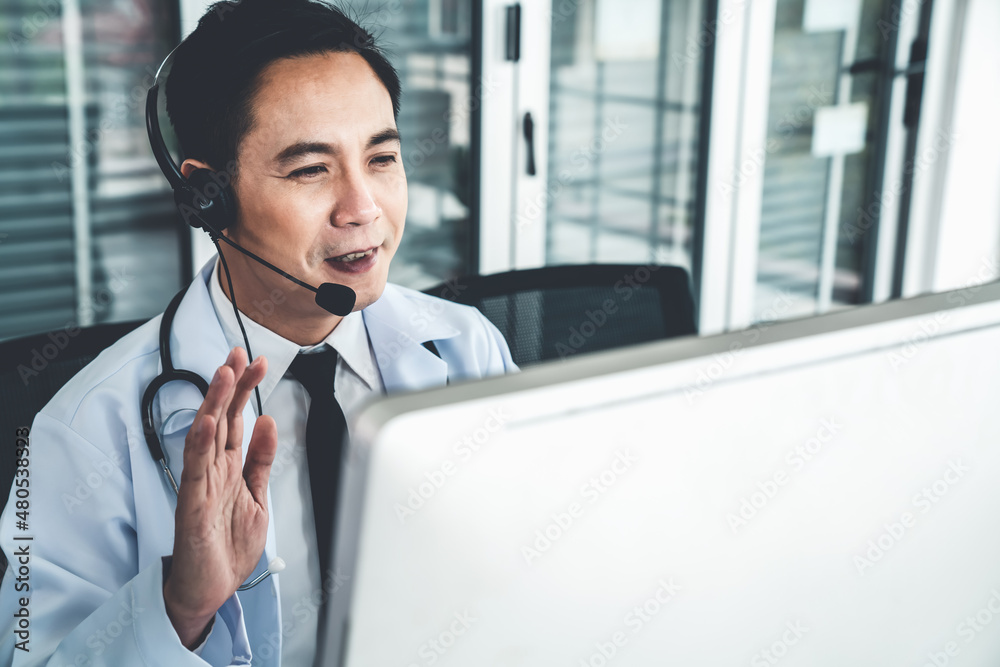 Doctor wearing headset talking actively on video call in a clinic or hospital . Concept of telehealt