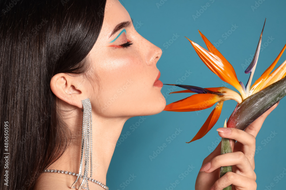 Beautiful young woman with strelitzia flower on color background