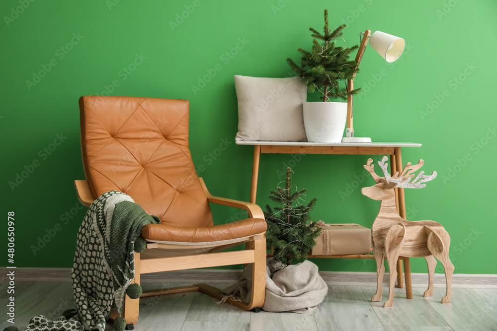 Interior of room with armchair, Christmas trees and reindeer near color wall