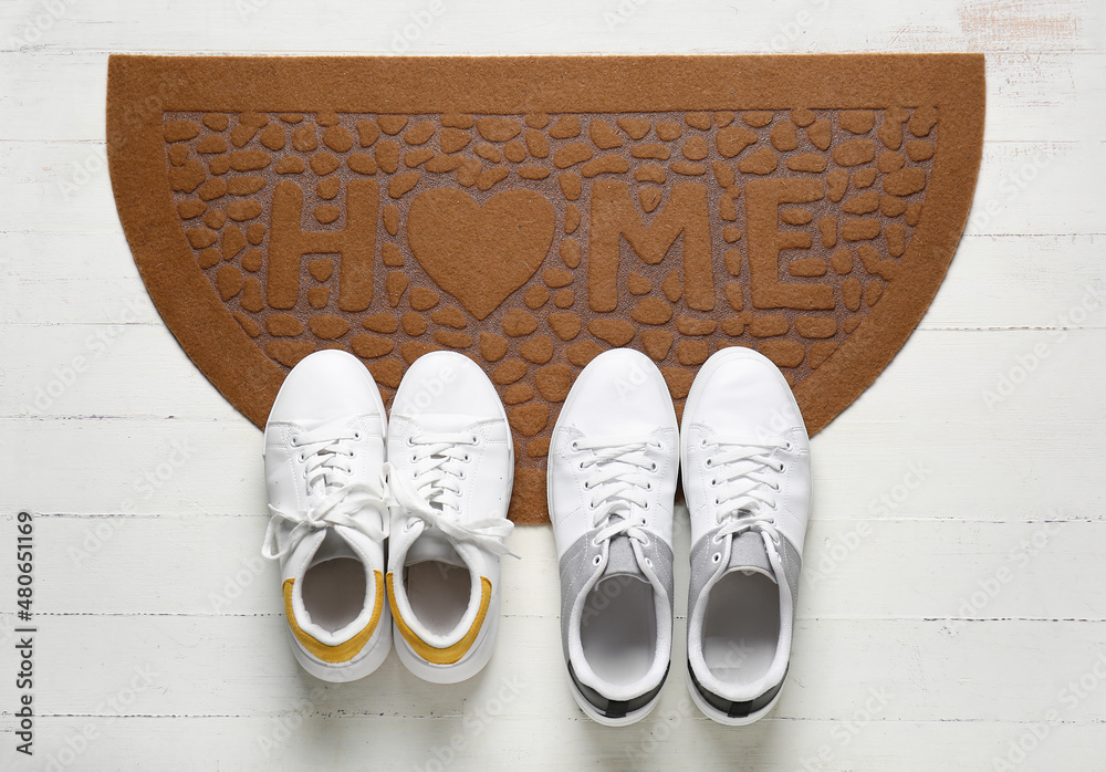 Door mat with sneakers on white wooden floor