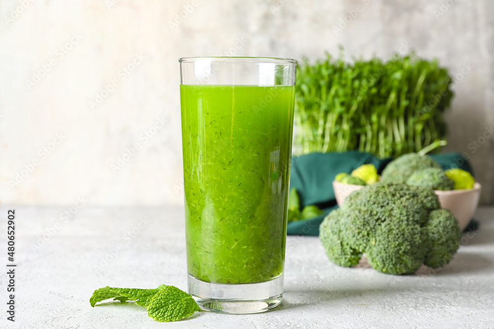 Glass of healthy green juice on light background