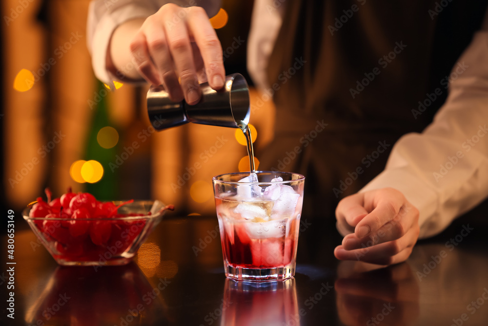 Bartender preparing tasty Manhattan cocktail at table in bar