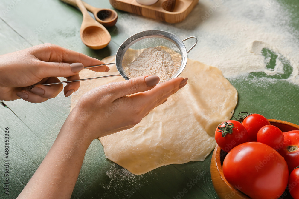 Woman preparing dough for tasty tomato galette at table