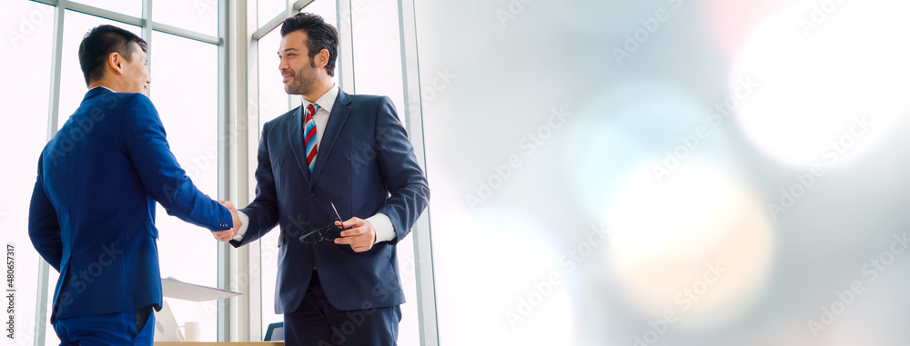 Business people handshake in corporate office in widen view showing professional agreement on a fina