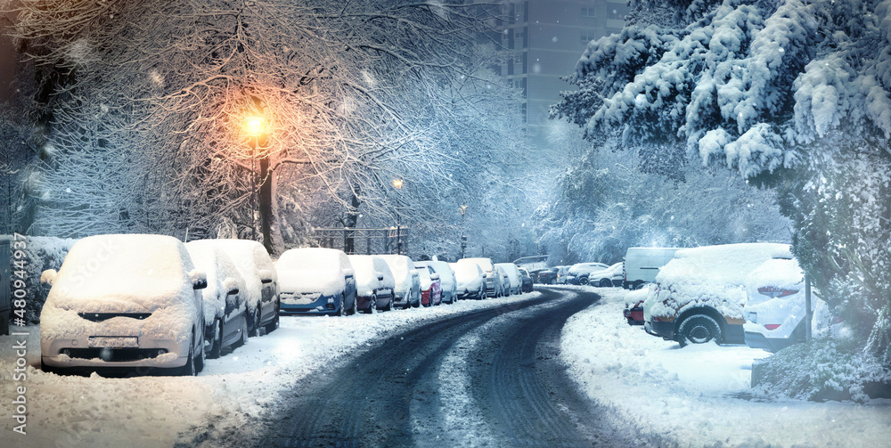 黄昏时，街道上停着被雪覆盖的汽车的城市冬季景象