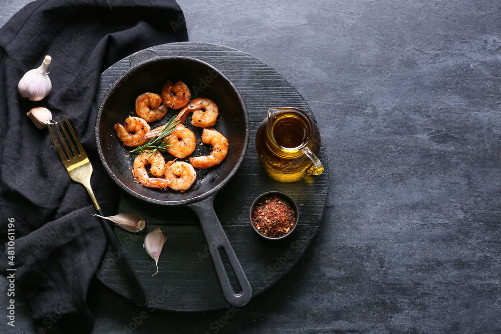 Frying pan of tasty shrimp tails on black background