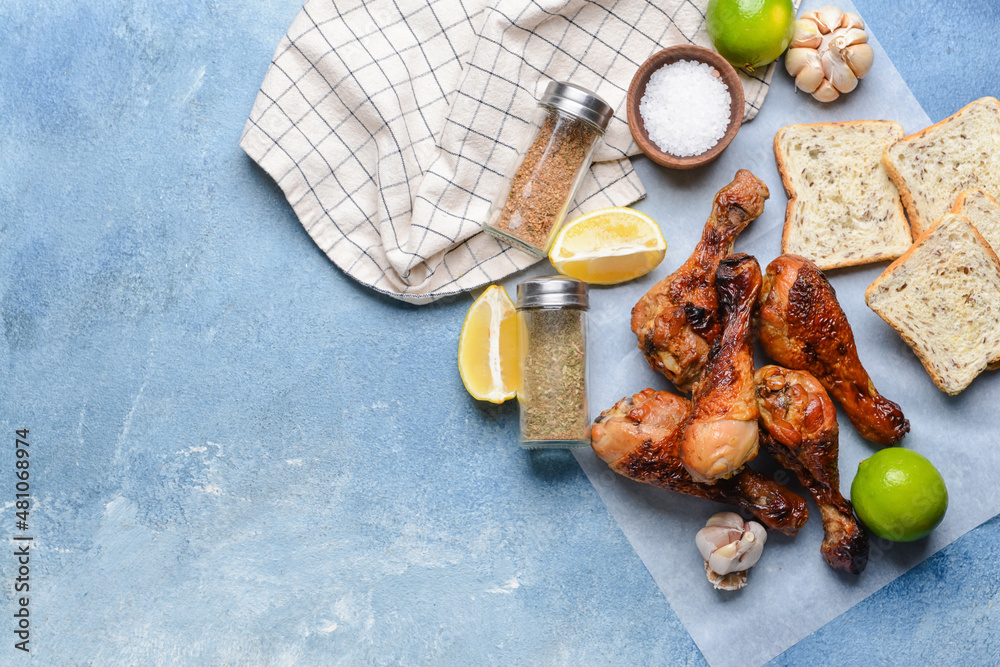 Tasty cooked chicken drumsticks with bread and spices on color background