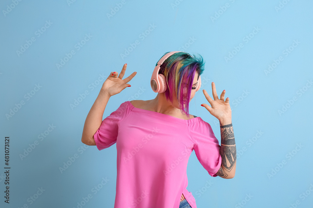 Beautiful woman with unusual hair listening to music on blue background