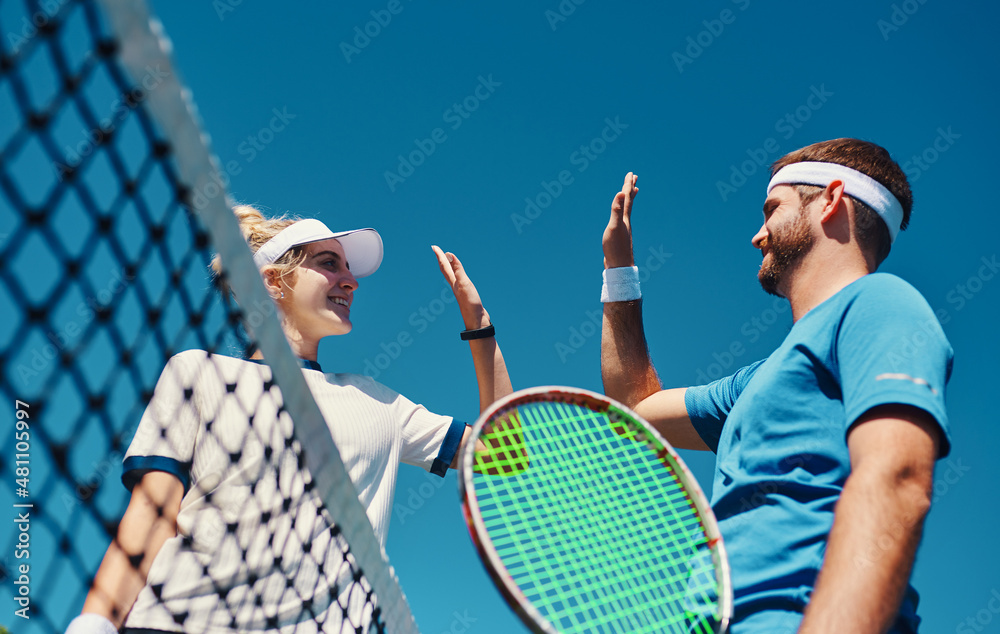 Talent wins games, teamworks wins championships. Low angle shot of two young tennis players giving e