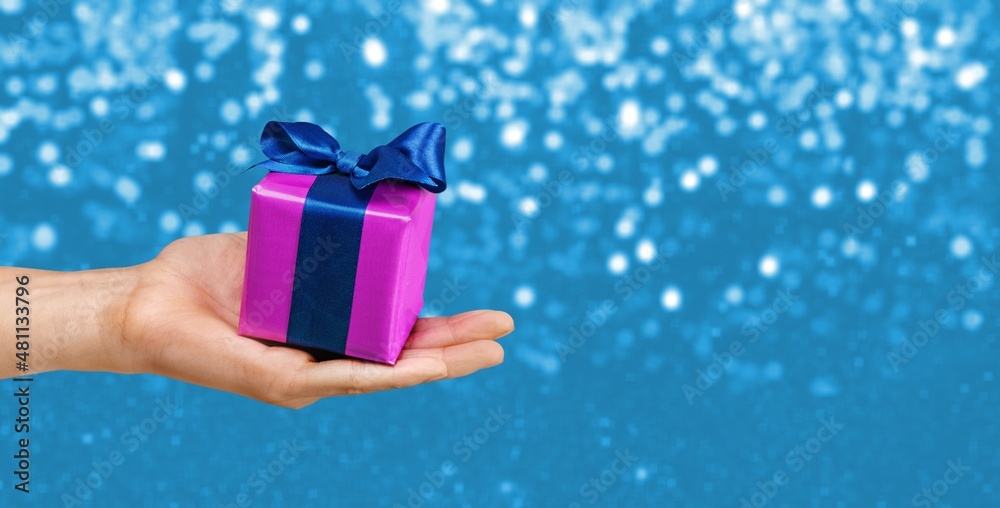 Hands holds Christmas gift on bokeh background