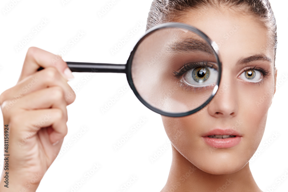 Magnifying her best features. Studio shot of a beautiful woman with a magnifying glass in front of h