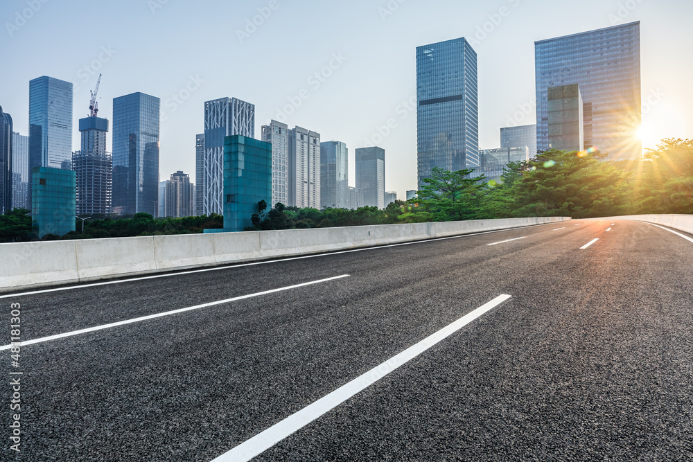 日出时，中国深圳的沥青道路和城市天际线，以及现代化的商业办公楼。